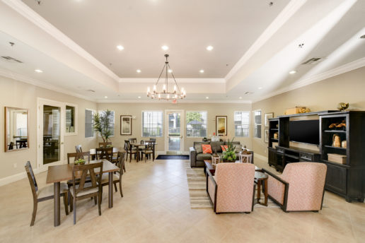 bright community room with seating areas, chandelier, television